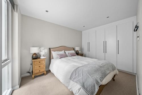 伦敦Captivating 3-Bed House in London Holland Park的白色卧室设有一张大床和一个床头柜