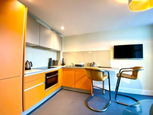 浦耳Incredible Apartment - Amazing Location - Free Parking & WiFi!的厨房配有橙色橱柜和桌椅