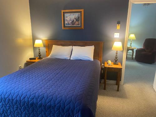 埃尔斯沃思Acadia Village Resort的一间卧室配有一张蓝色的床、两盏灯和一把椅子