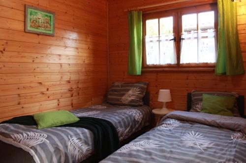 达布基Oaza Dąbek的小木屋内的两张床,设有窗户