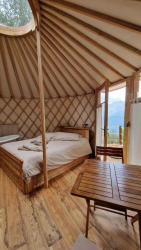 OstanaMonvisoRelax的蒙古包内一间卧室,配有一张床和一张桌子