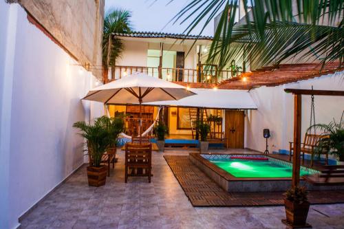 卡塔赫纳HOSTAL LA BOQUILLA的一个带游泳池、遮阳伞和椅子的庭院