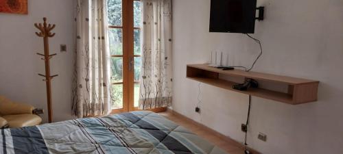 帕查卡马克Las buganvilias的一间卧室设有一张床、一台电视和一个窗口。