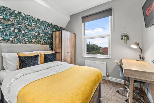 利兹5 Mins From Leeds - 4 Bed - Parking - Sleeps 9的一间卧室配有一张床、一张书桌和一个窗户。