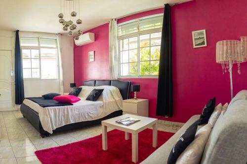 拜马欧La Villa Mussanda avec piscine的一间卧室配有一张床和粉红色的墙壁