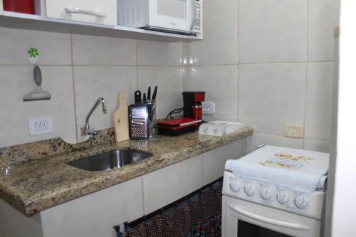 特拉曼达伊Apartamento à Beira-Mar e Centro Tramandaí Frente calçadão的厨房柜台设有水槽和炉灶。