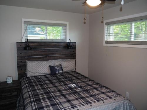 卡尔卡斯卡Manist-easy - Lakefront With Dock And Kayaks!的一间卧室配有一张带木制床头板的床和两个窗户。