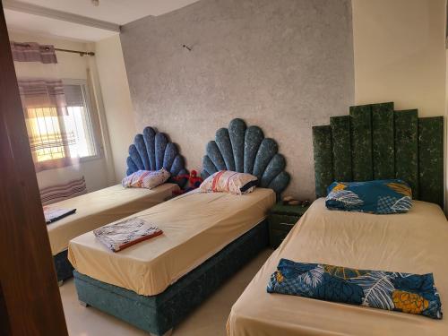 Al HachlafAppartement near airport ouled tayeb的一间卧室配有两张带蓝色靠垫的床。