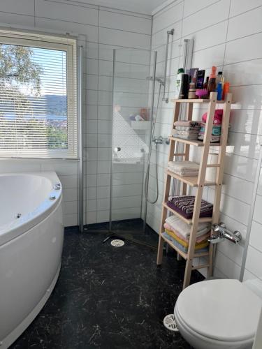 弗莱克菲尤尔Holiday home with seaview in Flekkefjord的带浴缸、卫生间和架子的浴室