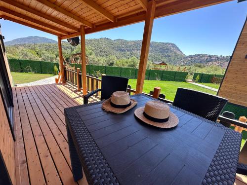 达拉曼Lake house kayacık Resort的两顶帽子坐在甲板上的木桌旁