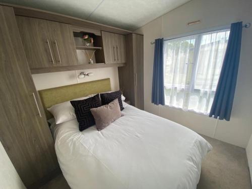 Saint OsythSerenity Holiday Home的卧室配有带枕头的白色床和窗户。