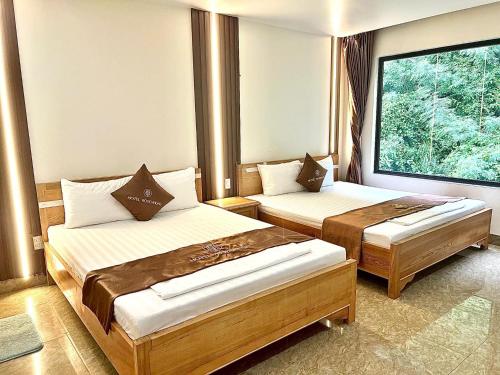吉婆岛Cat Ba Rose Nhung Hotel的酒店客房设有两张床和窗户。