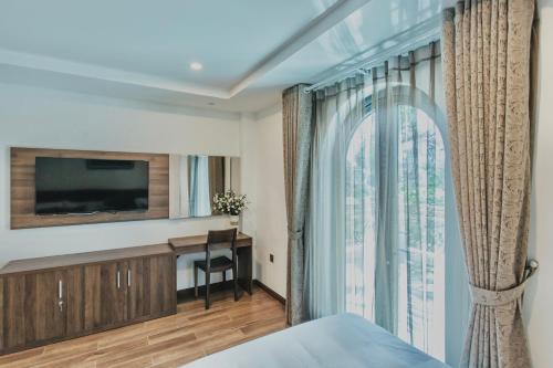 芽庄La Sera Suites Nha Trang的一间卧室设有一张床、一台电视和一个窗口。