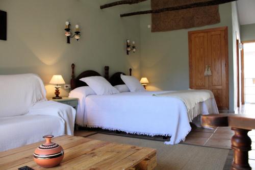 里奥帕尔恰罗德里欧默朵酒店的一间卧室配有两张带白色床单和桌子的床