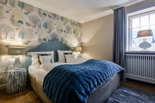 兰图姆Strandvogtei Sylt的一间卧室配有一张带蓝色毯子的床和窗户。