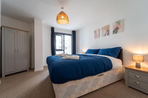 沃金Spacious Apartment in Woking Town Centre的一间卧室配有一张带蓝色床单的大床和窗户。