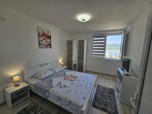 下米拉诺瓦茨Apartman Jovanovic的一间卧室配有一张床、一台电视和一个窗口