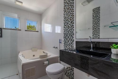 尼泰罗伊Casa incrível com 04 suítes - 5 min de Itacoatiara的浴室配有盥洗盆、卫生间和浴缸。