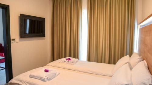 乌尔齐尼Apartments Montenegro Hills Ulcinj的两张位于酒店客房的床,上面有粉红色的鲜花