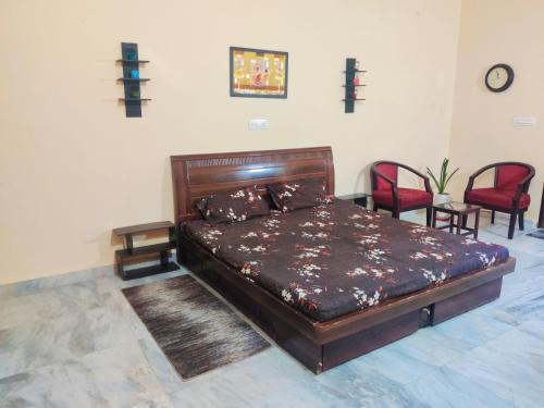 斋浦尔Luxurious 3BHK Urban Retreat Homestay的一间卧室配有一张带两把椅子的大型木床