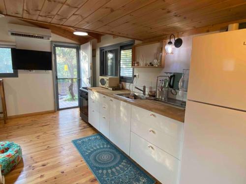Kefar DaniyyelBit cabin near the airport的厨房铺有木地板,配有白色冰箱。