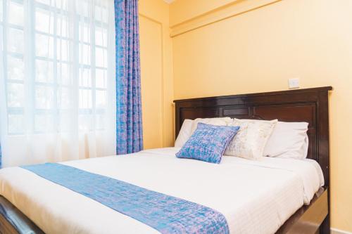 EmbuHaven Air BnB Embu的一间卧室配有一张带蓝色窗帘的床和一扇窗户
