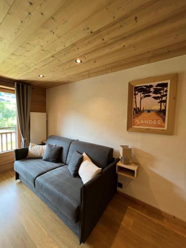 阿尔利河畔普拉兹Studio face aux pistes的客厅设有蓝色的沙发和木制天花板。
