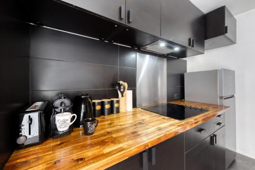 塞尔吉LE GARDEN -MAISON-2Parking-Jardin-Terrasse-Babyfoot-wifi的厨房配有木制台面和黑色橱柜