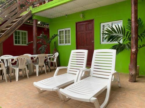 圣卡塔利娜岛Hostal Aguas Verdes的庭院设有白色椅子和绿色墙壁