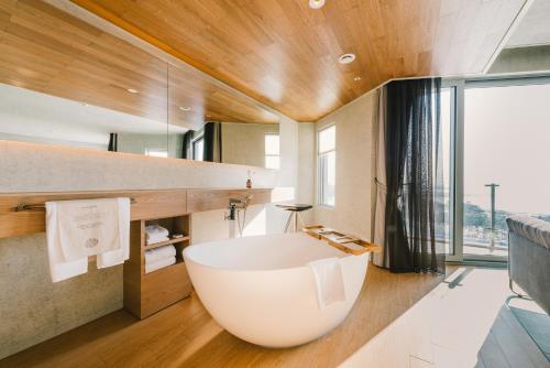 仁川市仁川鸟巢酒店的一间带大窗户的浴室内的白色大浴缸