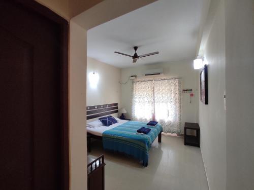 科尔瓦Beach Apartment 2,COLVA , GOA, INDIA的一间卧室配有一张带蓝色毯子的床和窗户。