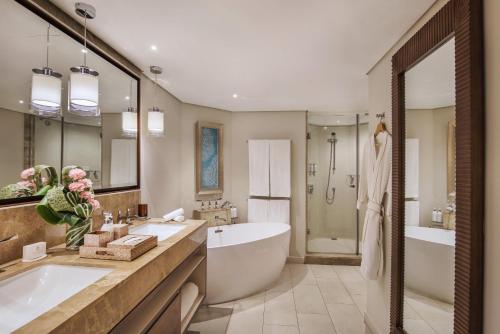 格兰贝伊Royal Palm Beachcomber Luxury的浴室配有2个盥洗盆、浴缸和浴缸。