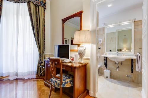 罗马Hotel Cellini的酒店客房设有一张带水槽和镜子的书桌