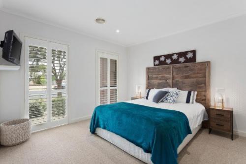 托基Golf Beach Retreat Torquay的白色卧室设有一张大床和电视。