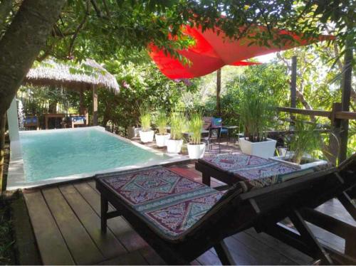 阿姆巴托洛阿卡Moemoea Lodge的一个带2个长椅和遮阳伞的游泳池
