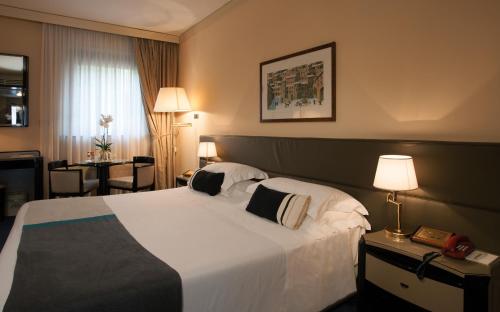 古比奥艾卡普契尼公园酒店的酒店客房设有一张大床和一张桌子。