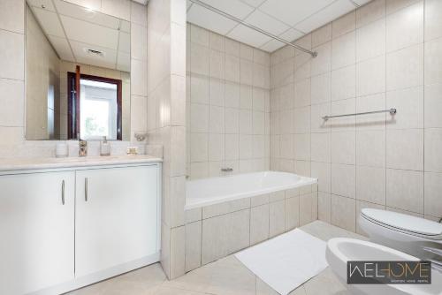 迪拜WelHome - Prime Apartment With Balcony Amidst Lively Area的白色的浴室设有浴缸和卫生间。