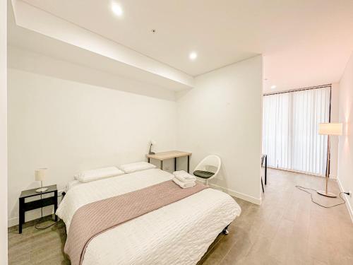 悉尼Burwood Studio的白色卧室配有床和书桌