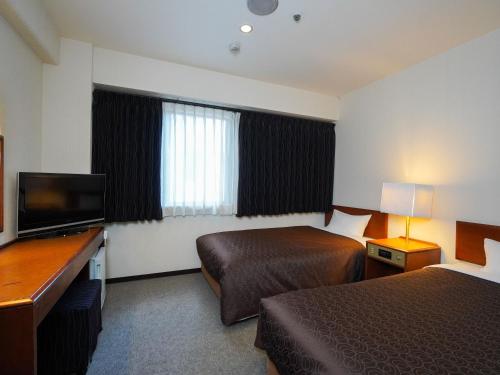 福冈Plaza Hotel Tenjin的酒店客房设有两张床和一台平面电视。
