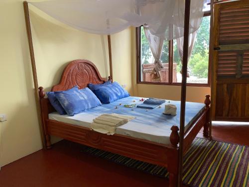 UtendeMafia Beach Bungalows sea view的一间卧室配有一张带蓝色枕头的天蓬床