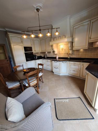 布永Gîte L'Hôte-Antique的厨房配有白色橱柜和桌椅