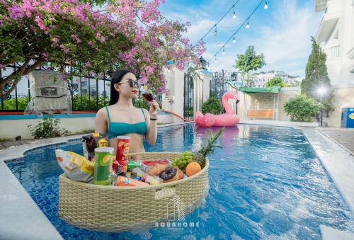 下龙湾The An Nam Villa HaLong的坐在游泳池里,拿着一篮子食物的女人