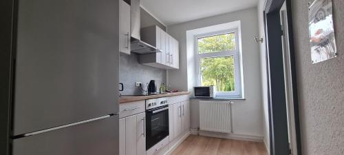 施托尔贝格Workers apartment in Stolberg的厨房配有白色橱柜和窗户。