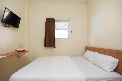班达楠榜AVA Guesthouse Mitra RedDoorz Lampung的卧室配有白色的床和电视。