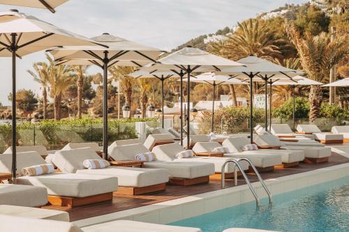 圣埃乌拉利亚Hotel Riomar, Ibiza, a Tribute Portfolio Hotel的游泳池旁的一排躺椅和遮阳伞