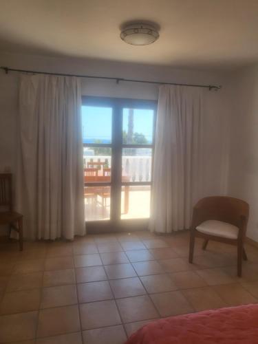 圣埃乌拉利亚Siesta el por del sol的客房设有带窗帘和椅子的窗户。