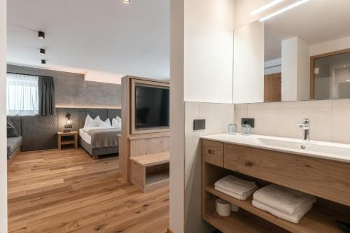 奥蒂塞伊Hotel Niblea Dolomites的一间带水槽的浴室和一间带一张床的卧室