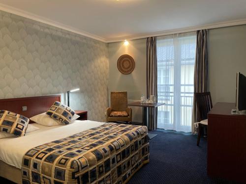韦尔特African Sky Hotel的配有一张床、一张书桌和一扇窗户的酒店客房