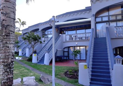 马盖特Uvongo cabanas的一座拥有蓝色楼梯和棕榈树的建筑