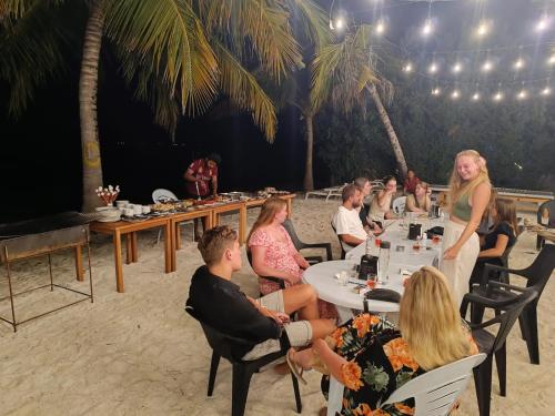 迪弗西The Sunset Villa的一群坐在海滩桌子上的人